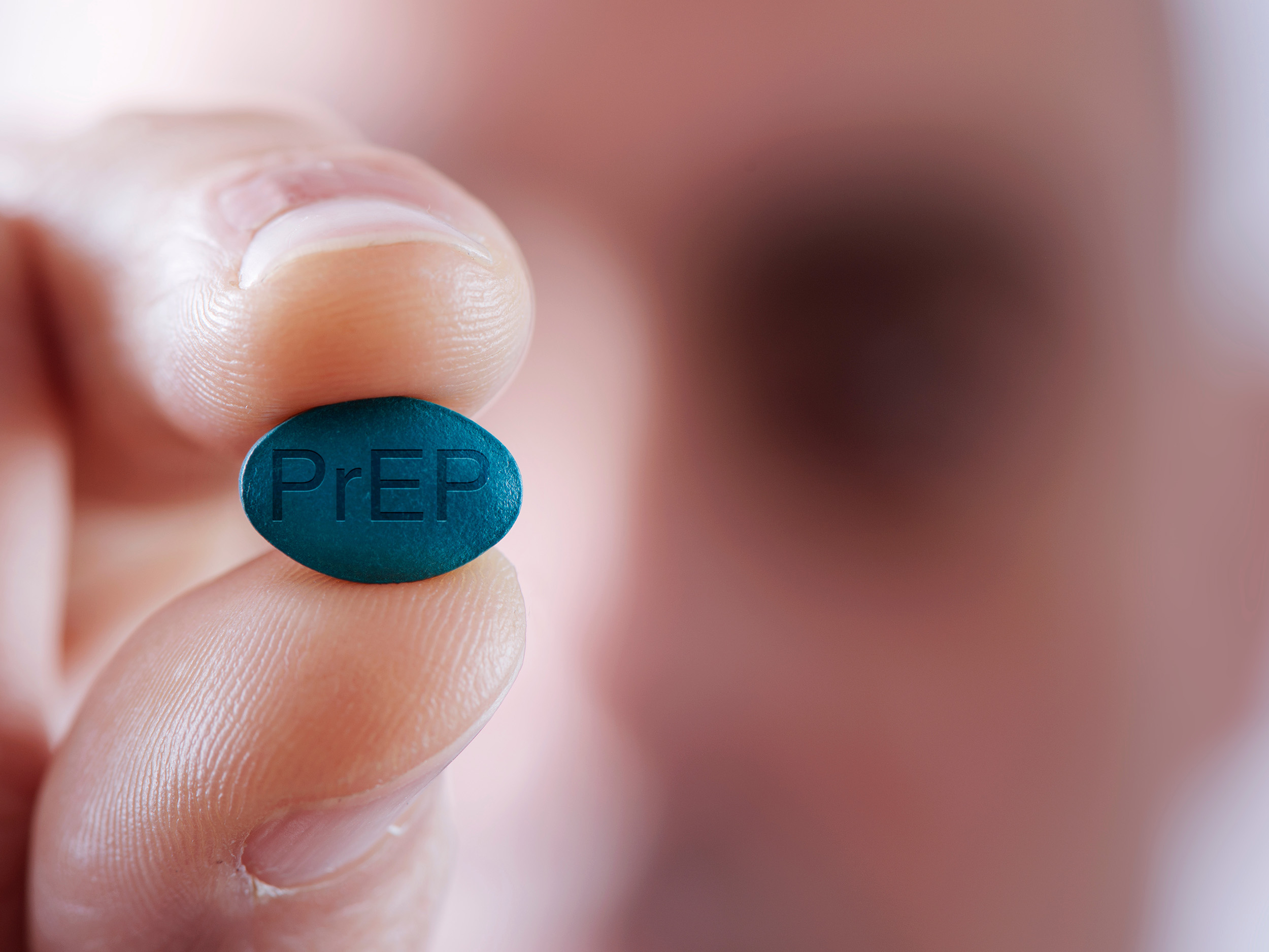 Close up of man holding a PrEP pill